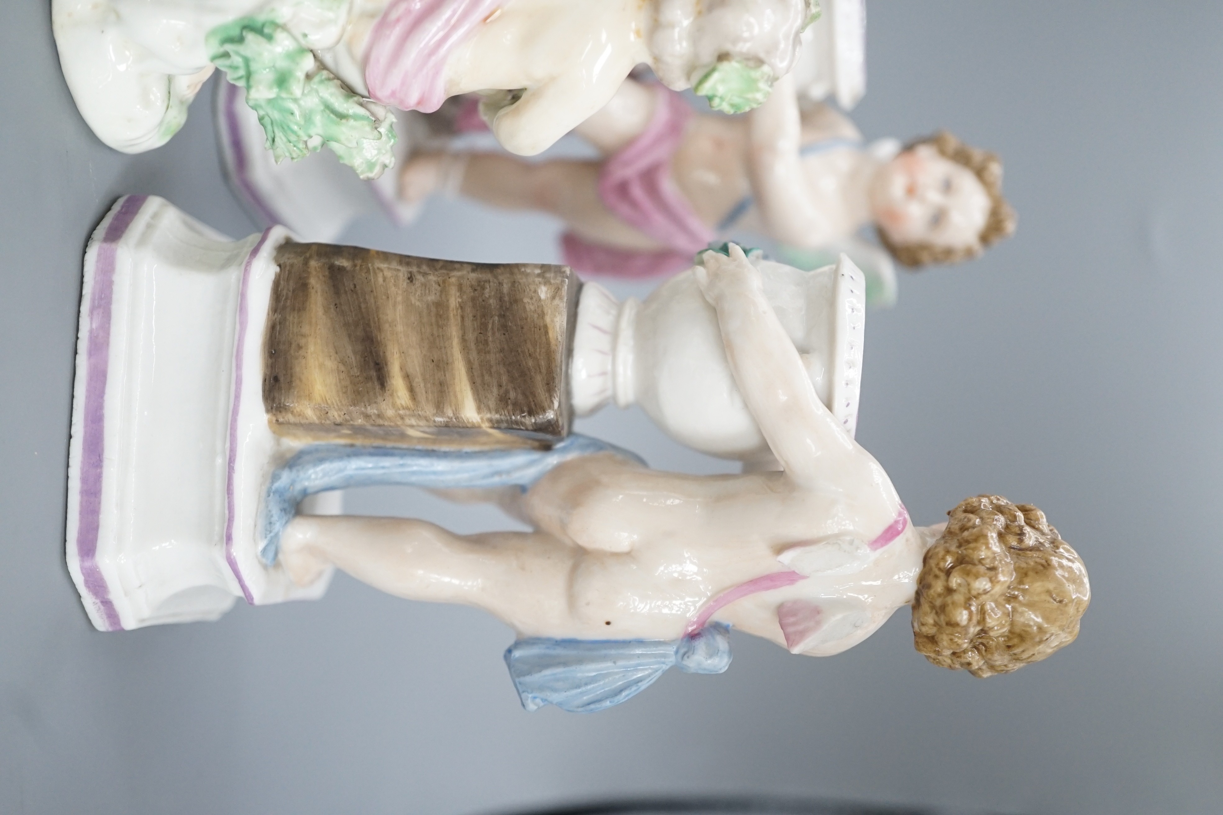 A pair of Continental porcelain cherub candlesticks, 13.5cm, a figural bonbon and a Derby figure